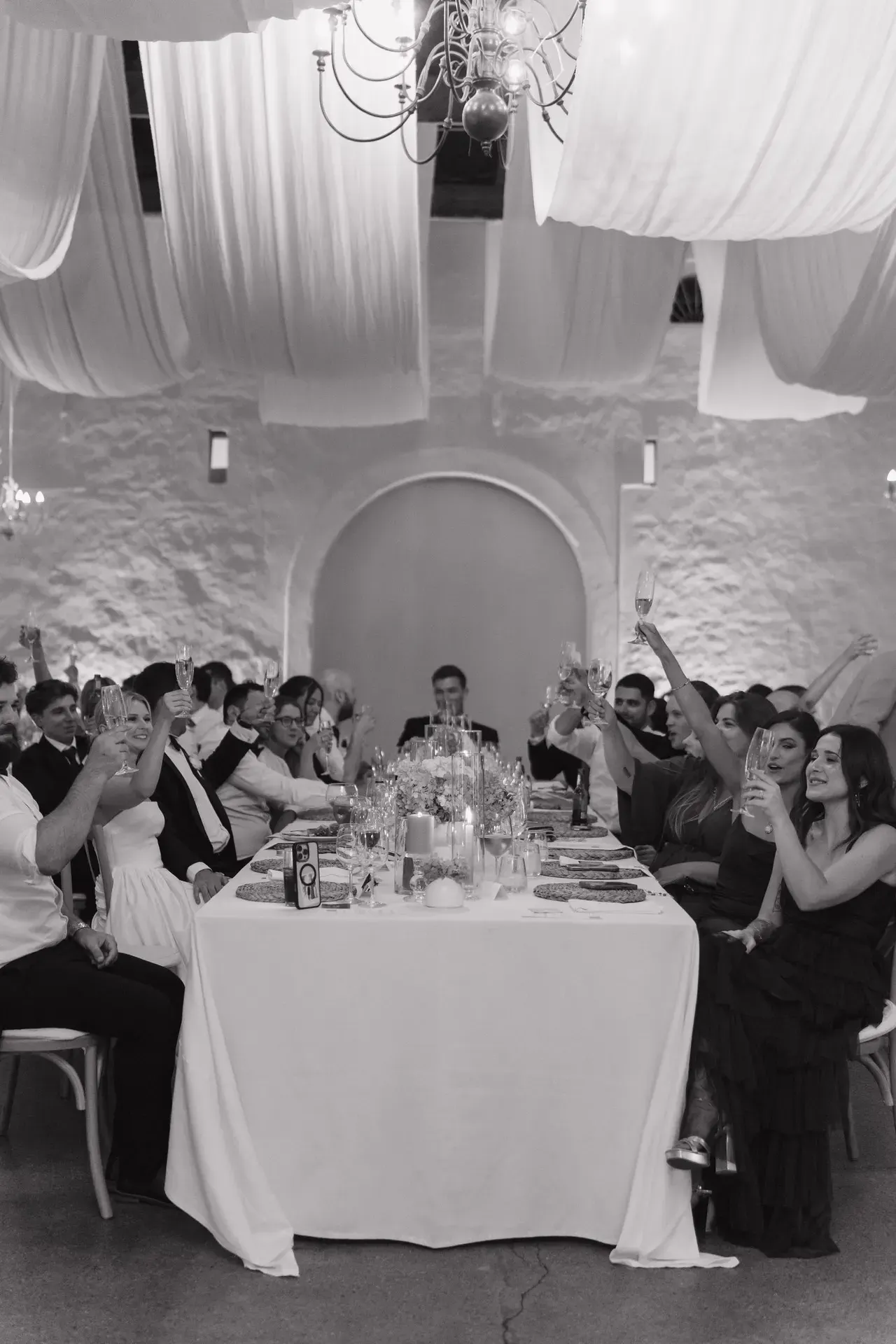 Black-and-white reception moment: guests raising a toast at Mark & Amy's wedding